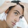 Man inspecting hair loss in mirror